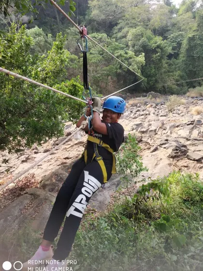 A young adventurer gives a thumbs-up while enjoying a zipline at the summer camp.