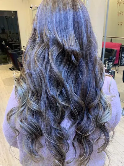 This is a perfect example of a cool-toned balayage with soft, beachy waves. We specialize in creating these custom-blended looks that grow out beautifully and give the hair a natural, sun-kissed dimension.
