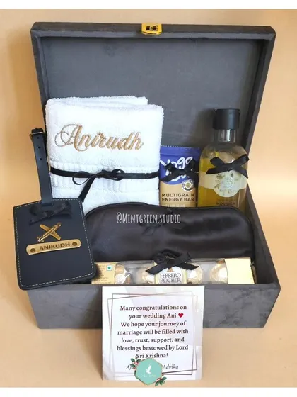 We design elegant and sophisticated gift hampers to celebrate a wedding. This one, packed in a premium grey suede box, includes personalized towels, a custom luggage tag for the honeymoon, and other thoughtful items for the happy couple.