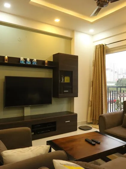 This view shows the TV unit and seating area in a modern home. The dark wood furniture provides a rich contrast to the light-colored walls and flooring.
