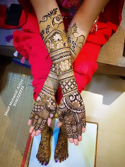 A beautiful bridal design featuring a prominent peacock on the forearm, surrounded by floral and geometric patterns.