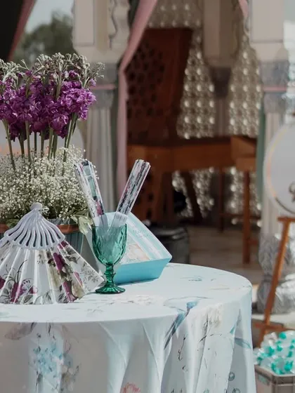 A small table with themed party favors, including floral-printed fans. Even the smallest details are designed to align with the romantic garden party theme.
