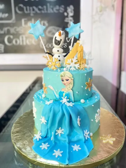 A beautiful two-tiered cake inspired by Disney's Frozen. This design features Queen Elsa, a flowing fondant dress, and delicate snowflake details.