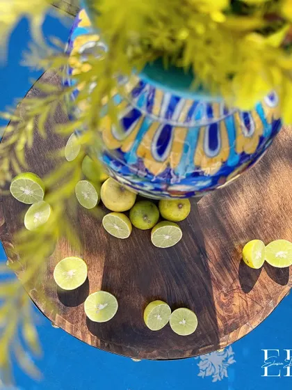An artistic overhead shot of sliced limes on a wooden table, with a beautifully painted ceramic vase in the background, capturing the fresh and zesty essence of the event.
