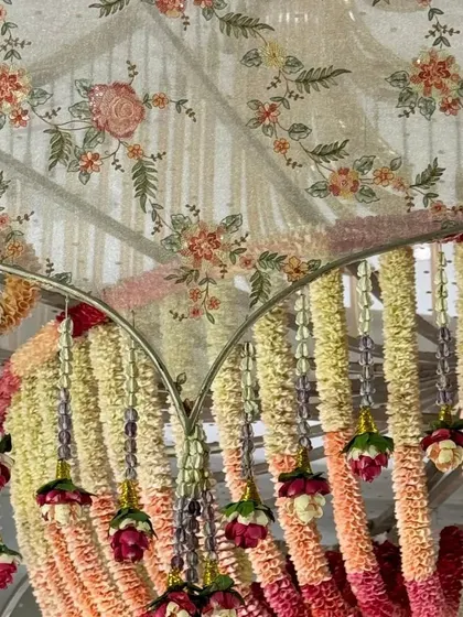 A detail of the floral canopy from the 'Janavasam' event. The hanging arrangements of fresh flowers in shades of pink and cream create a beautiful, fragrant ceiling for the celebration.