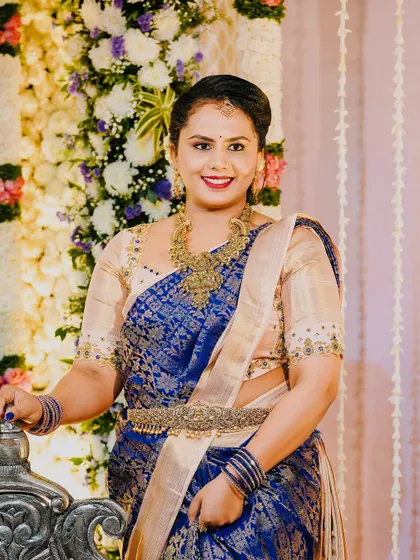 A happy client at a wedding, wearing a royal blue Kanjeevaram saree with a simple yet elegant beige embroidered blouse.