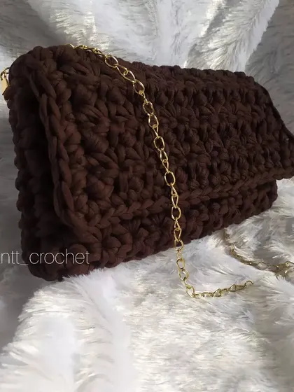 For a more structured and elegant look, I use chunky T-shirt yarn. This brown clutch has a sturdy feel and is paired with a gold chain strap, making it perfect for evenings out.