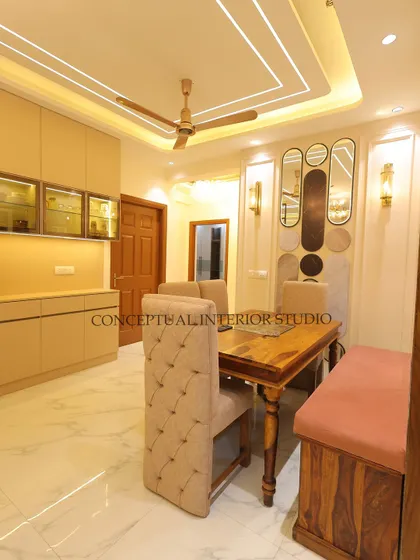 This dining area combines traditional and modern elements, with a classic wooden table set against a contemporary wall with unique mirrors and a built-in crockery unit.