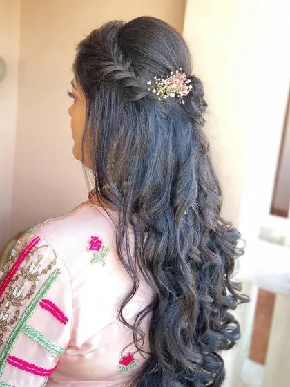 A simple braided half-up style with loose waves, accented with a small floral clip.