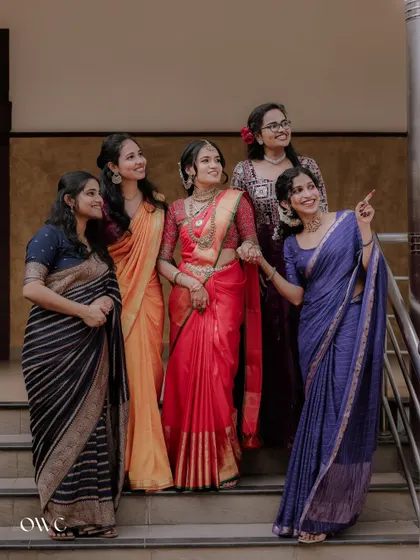 A beautiful portrait of a bride and her bridesmaids on a staircase, all dressed in colorful sarees.