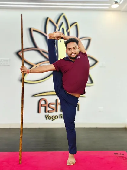 Stick yoga is excellent for improving balance and flexibility. Here, a student uses a stick to assist with a standing split variation.