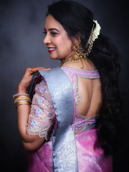This side profile highlights the beautiful back details of the blouse and the classic hairstyle, adorned with traditional hair accessories.