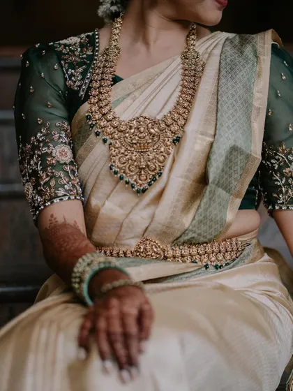 A detail shot focusing on the intricate floral embroidery on the sheer sleeves of the green blouse.