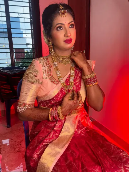 This bride is ready for her ceremony, showcasing a beautiful look with a bright pink lip that pops against her elegant saree. The makeup is designed to be long-lasting and picture-perfect.