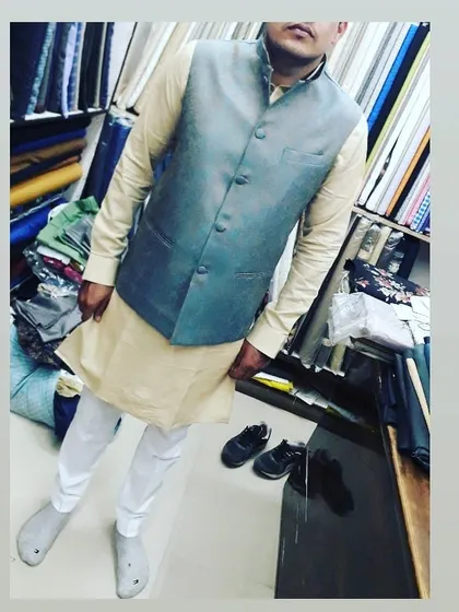 A client wearing a grey textured Nehru jacket over a beige kurta. This shows the front view of the outfit, highlighting the fit and fabric.