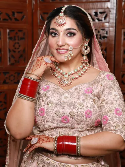 A beautiful bride in a pastel peach lehenga. The makeup is soft and glowing, with a focus on a flawless complexion and a happy smile.