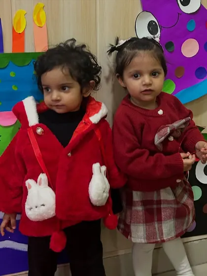 Two little friends dressed in red and white for the festive season stand together during a birthday party.