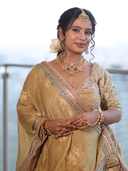A full portrait of the bride in her golden lehenga. The makeup, hair, and draping all come together to create a look of timeless grace.