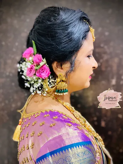 An elegant messy bun decorated with fresh pink roses and baby's breath. This is a versatile hairstyle that works beautifully for receptions or traditional functions.