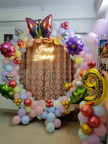 A whimsical and colorful balloon ring for a 9th birthday. This decoration uses a variety of pastel balloons and is adorned with large butterfly and flower foil balloons.