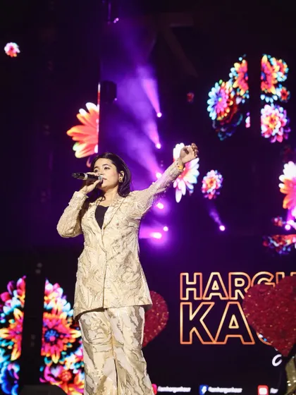 Hargun Kaur raising her hand to the crowd, with a beautiful floral graphic on the screen behind her. I always incorporate the stage's visual elements into my compositions.