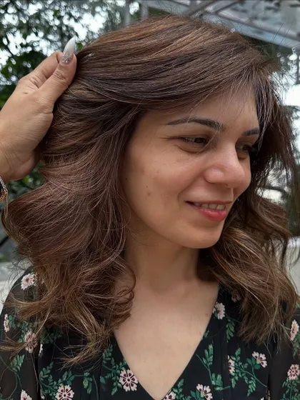 A happy client with her fresh 'Caramello' color and a bouncy, layered cut.