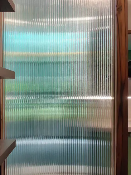 A detail of a fluted glass partition, which provides privacy while allowing light to pass through, creating beautiful distorted patterns.