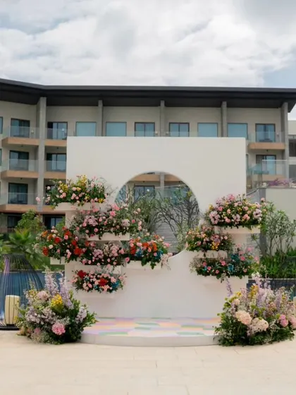 A beautiful floral photo backdrop with a circular cutout, set against the pool and hotel building.
