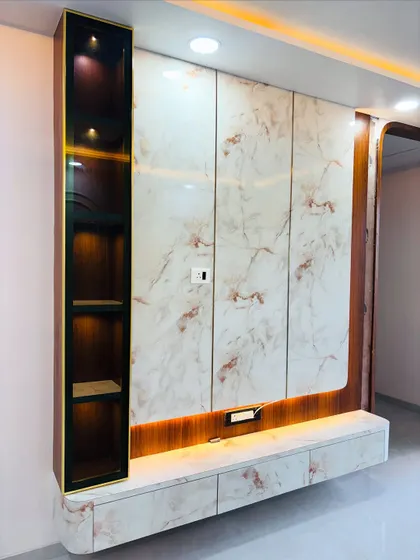 A luxurious TV unit design featuring a full marble-finish wall with gold inlay details. The floating console and the lit-up vertical display shelf on the side add to the high-end look.