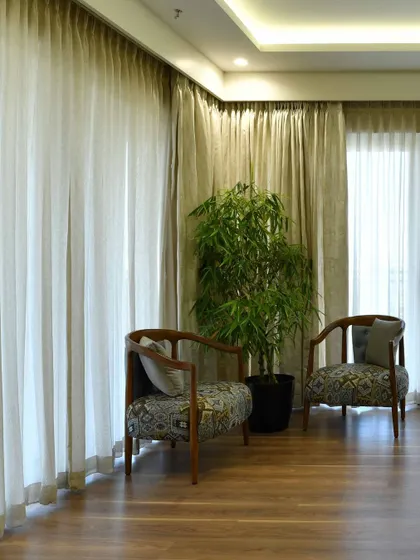 A cozy corner in the master bedroom with patterned accent chairs and sheer curtains. This space is perfect for morning coffee or quiet reading, adding another layer of function to the room.
