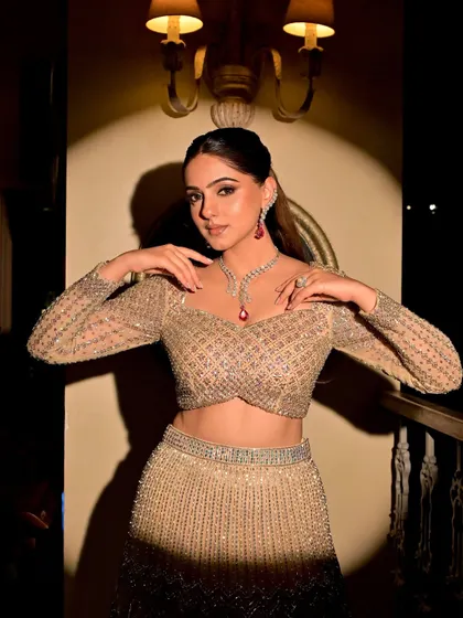 A dramatic shot capturing the full essence of this modern sangeet glam. The spotlight highlights the intricate details of her outfit and the radiant finish of the makeup.