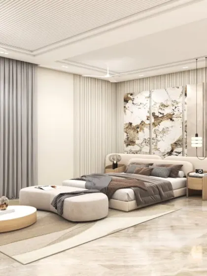 A luxurious master bedroom featuring a wide, upholstered headboard, elegant wall paneling, and a soft, neutral color scheme. The space is designed to feel expansive and serene, with marble flooring and ample natural light.