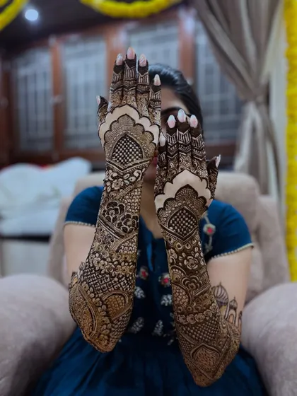 A lovely shot of the bride hiding behind her beautifully hennaed hands.