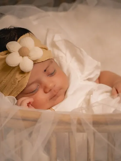 A peaceful portrait of a sleeping infant, adorned with a simple floral headband. I use soft, diffused light to gently illuminate the baby's features without disturbing their rest.