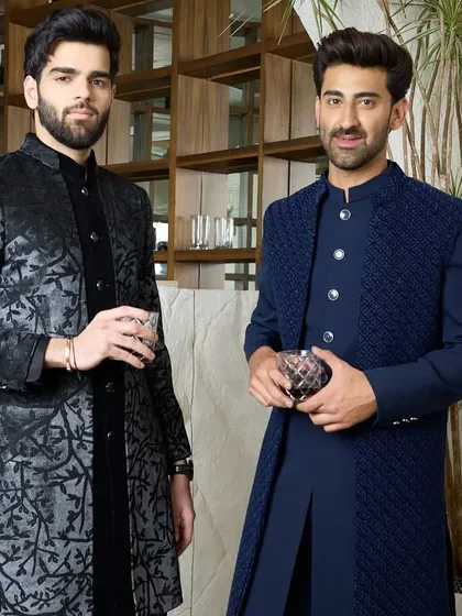 Two examples of evening elegance. On the left, a black kurta with a subtle, shimmering pattern, and on the right, a navy blue layered Indo-Western set with a textured jacket.