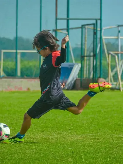 A young athlete winding up for a powerful kick, showcasing the fundamental skills we nurture in our youth leagues.