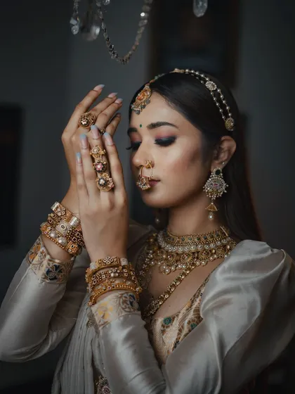 A close-up portrait focusing on the intricate details of the bride's jewelry and makeup. Her pose is elegant and serene, reflecting the beauty of the moment.