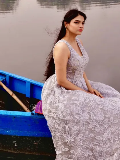 A profile shot showcasing the elegant neckline and intricate lace detail of the custom grey gown. The wind catching the hair adds a natural, effortless feel to this styled portrait.