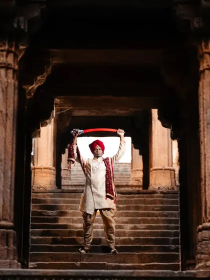 A powerful solo portrait of the groom in a heritage setting. Standing on the steps of the haveli with a sword, this shot has a majestic and commanding presence, fit for a king.