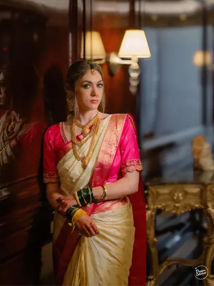 A moody and elegant portrait of the bride in her traditional saree, using the warm, dim lighting of the hotel to create a classic feel.