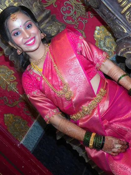 A full-length portrait showcasing a stunning pink silk saree against a richly decorated wall. I pay close attention to lighting to make the fabric and jewelry shine.