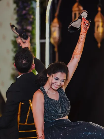 A joyful moment from the shoe game, as the bride raises her shoe in triumph, sharing a laugh with her new husband and all their guests.