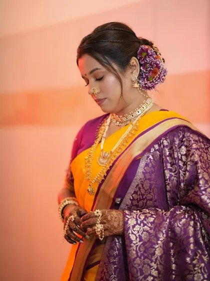 A serene moment captured. The bride looks down, showcasing her soft eye makeup and the intricate details of her floral hair arrangement.