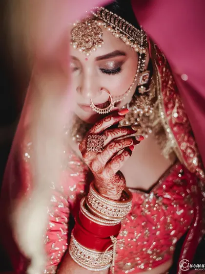 A close-up shot of the bride's face and hands, focusing on the delicate details of her makeup, nose ring, and henna.
