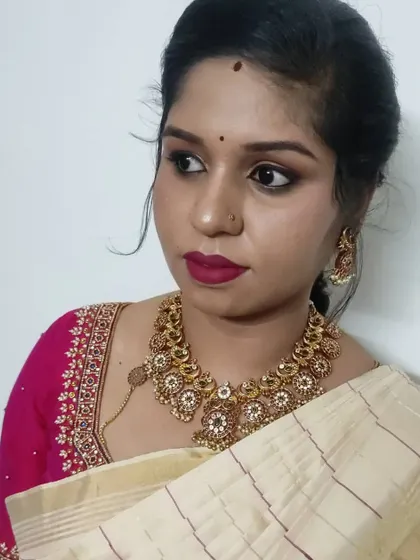 A simple and elegant look for a family function. This features a smokey eye, a bold berry lip, and a classic hairstyle that works beautifully with her off-white and pink silk saree.