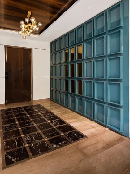 A full view of the blue coffered panel wall in the entryway. This element serves as both a powerful design statement and a clever way to integrate shoe storage seamlessly into the foyer.