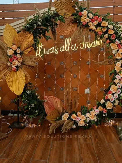 A romantic and dreamy photo booth for an engagement or reception. The floral hoop is accented with dried pampas grass and a neon sign, all set against a backdrop of fairy lights.