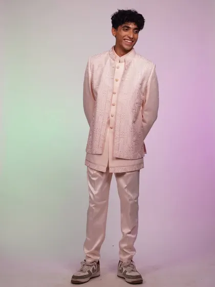 A full-length shot of the pink Indo-western set. The modern silhouette and soft color make it a unique and stylish choice for a wedding guest.