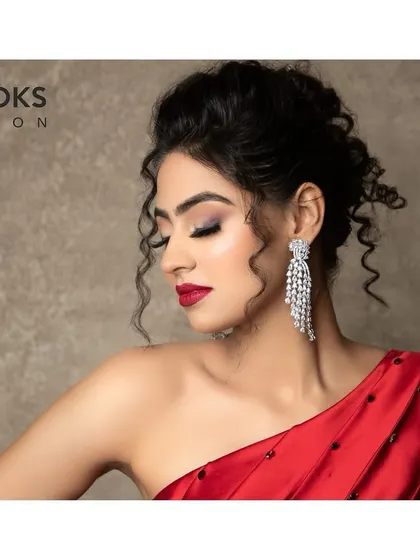 A side profile showcasing the elegant updo and shimmering eyeshadow of this party look. The subtle glow on the cheekbones and the classic red lip complete this sophisticated style.