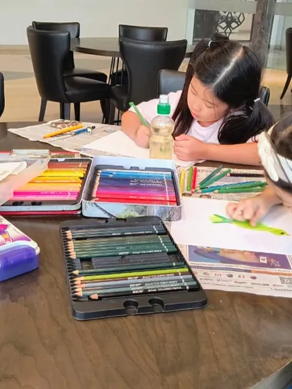A wide shot of the parrot drawing class, showing students focused on their work with all the necessary art supplies at hand.
